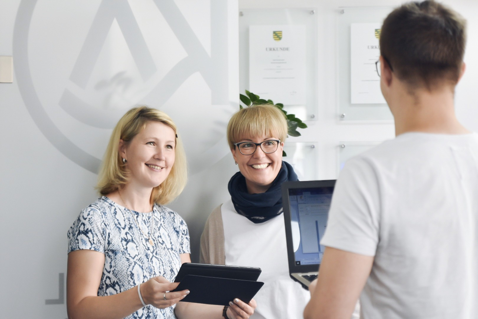 Drei Kollegen aus dem Team kalkül begegnen sich uns lächeln sich an
